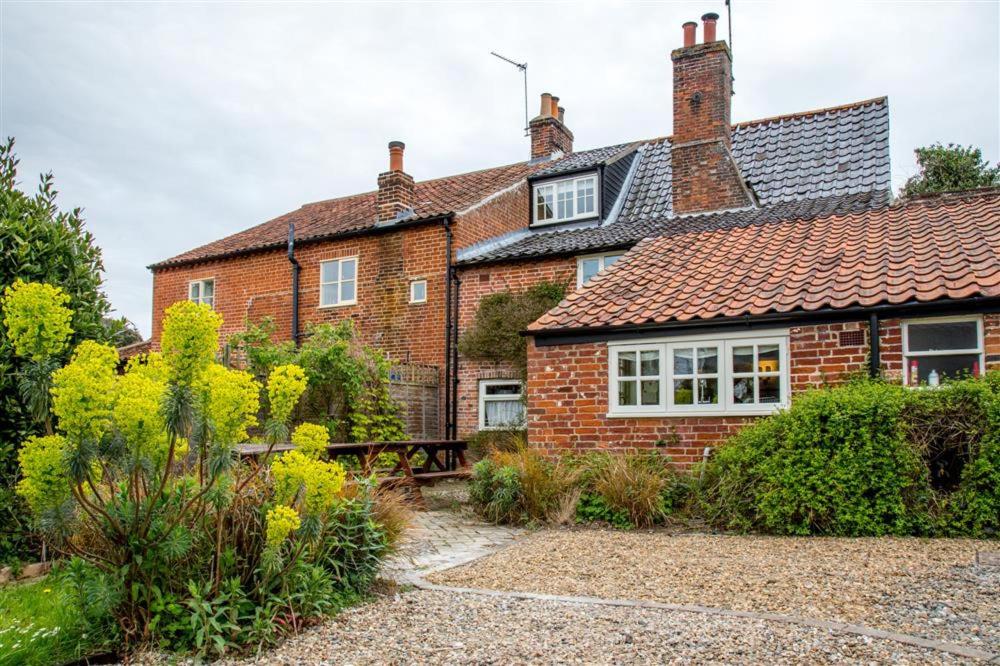 een bakstenen huis met een tuin ervoor bij Dressmakers Cottage in Wrentham