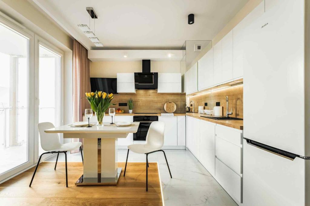 a kitchen with white cabinets and a table and chairs at Apartament Centrum Plac Litewski 21 in Lublin