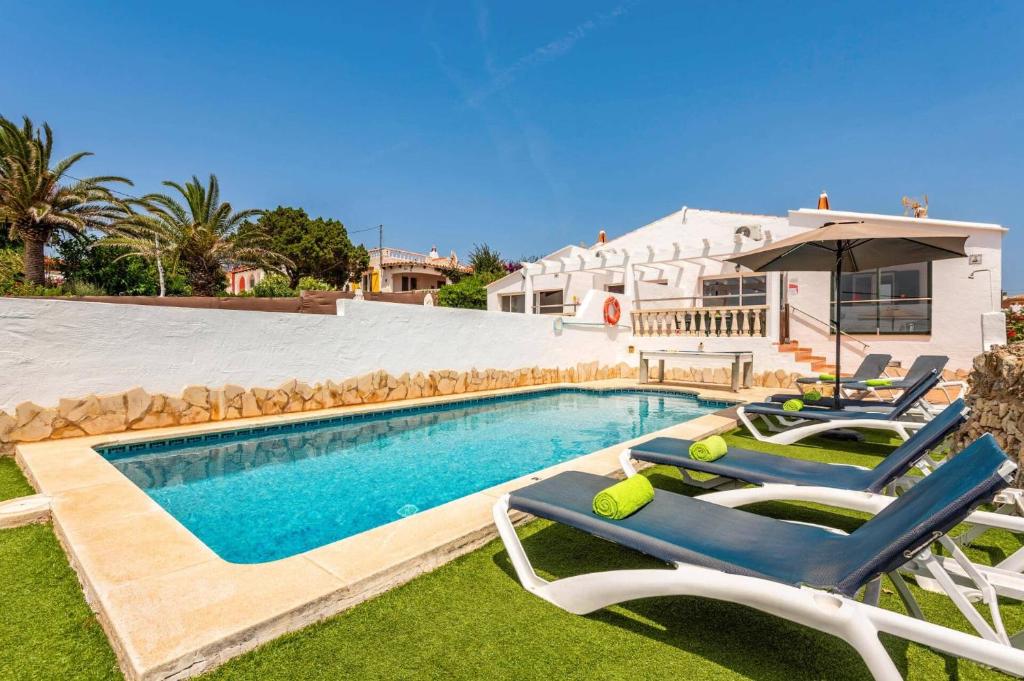 a swimming pool with lounge chairs and a house at Villa Maru II by Villa Plus in Cala en Porter