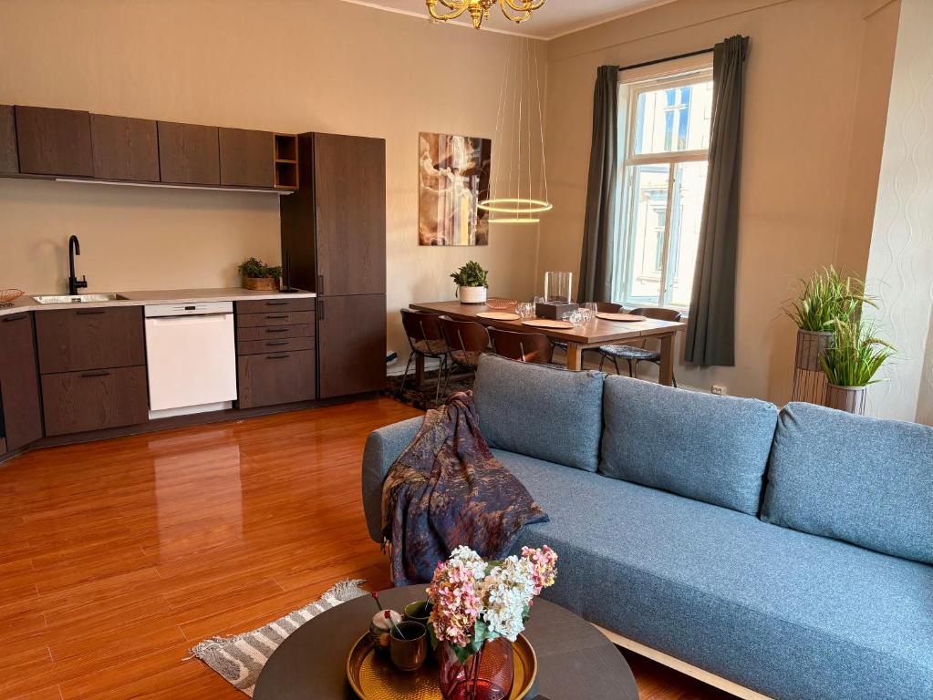 a living room with a blue couch and a kitchen at Charming apartment Nygårdsparken in Bergen