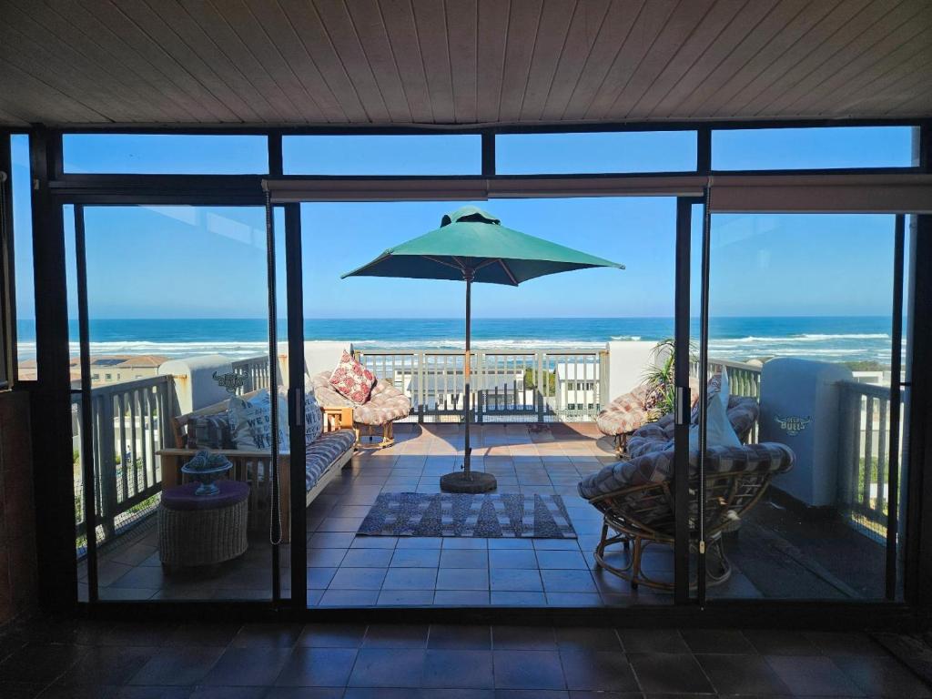 a view of the ocean from a balcony with an umbrella at Bee Unique in Sedgefield