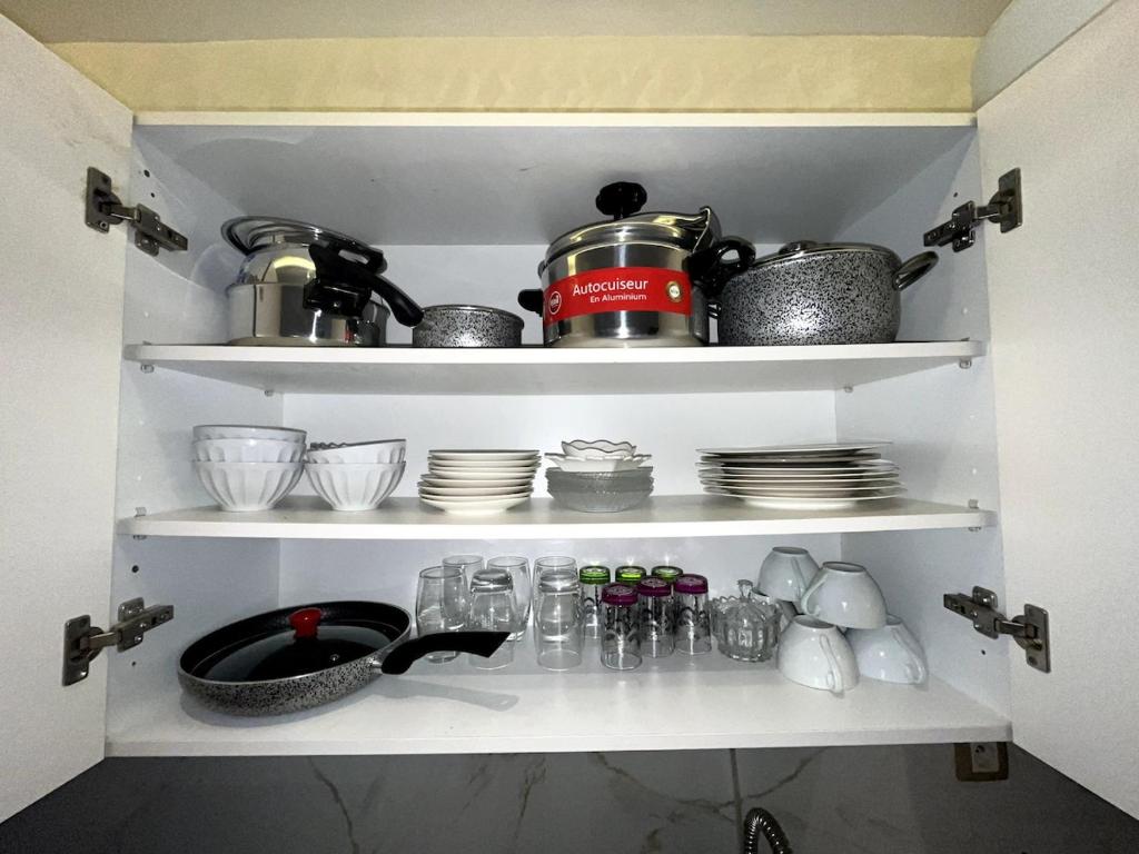 a shelf with cups and dishes and a pot on it at Abdellah Tabrikt in Kenitra