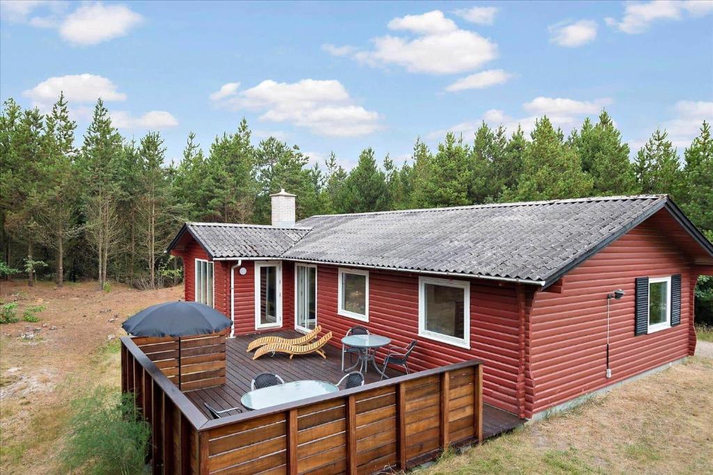 a red house with a deck with a table and chairs at 0127-Romo-Umanaksvej-4 in Høm