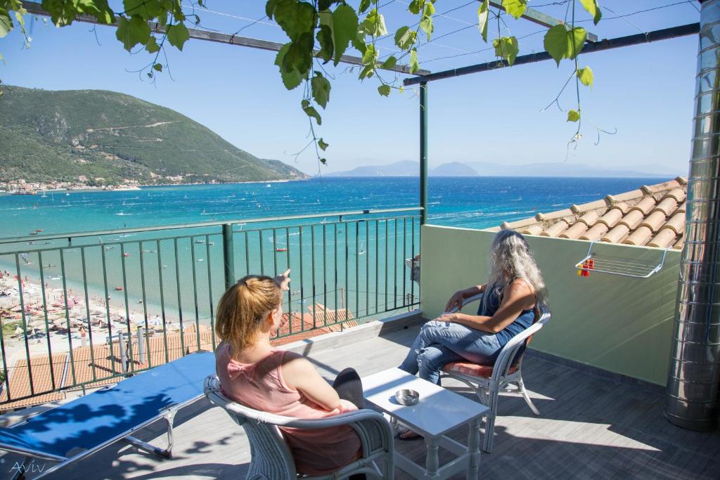 two women sitting on a balcony looking at the beach at Steven in Vasiliki