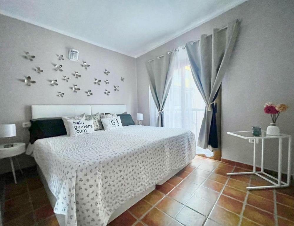 een slaapkamer met een wit bed met vogels aan de muur bij Apartamentos Magdalena in Valle Gran Rey