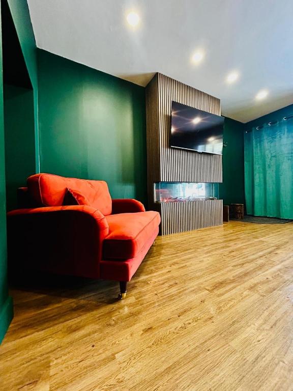 a living room with a red couch and a fireplace at The Green Room in Tideswell