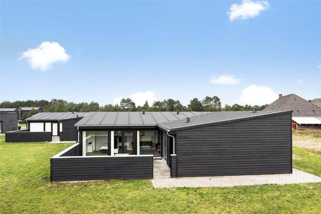 una casa nera in cima a un campo verde di 0342-Romo-Vestergade-355 a Sønderby