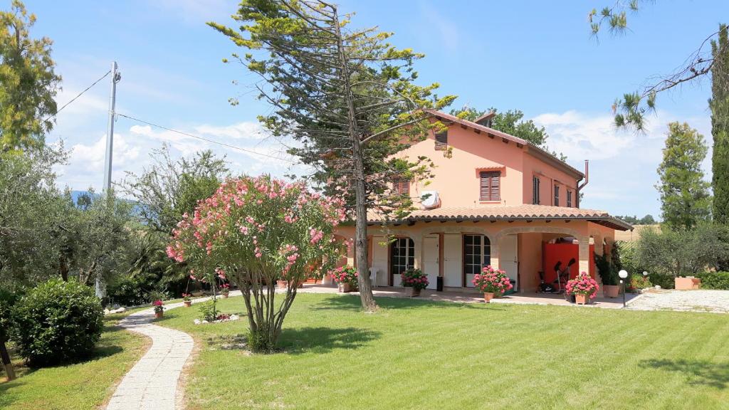 a pink house with a yard with a tree at La Casa in Campagna in Cossignano