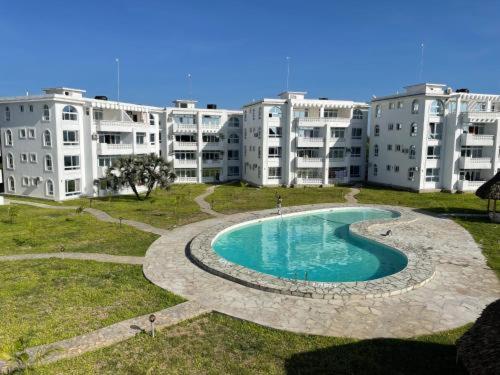 a swimming pool in front of a large apartment building at Kijani unique home Malindi in Malindi