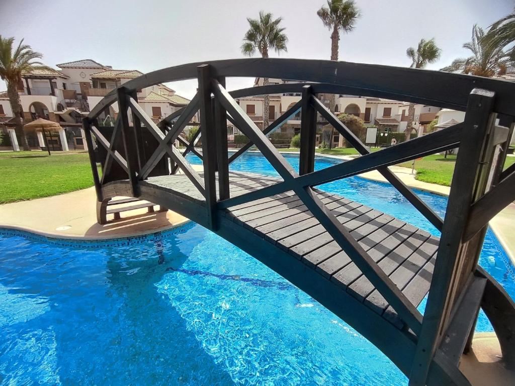 a bridge over a pool with blue water at Veradreams SPA thalassa in Playas de Vera