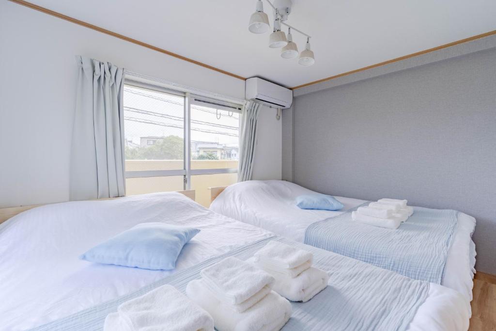 two beds in a room with white sheets and towels at IJIRIGoodStay in Fukuoka