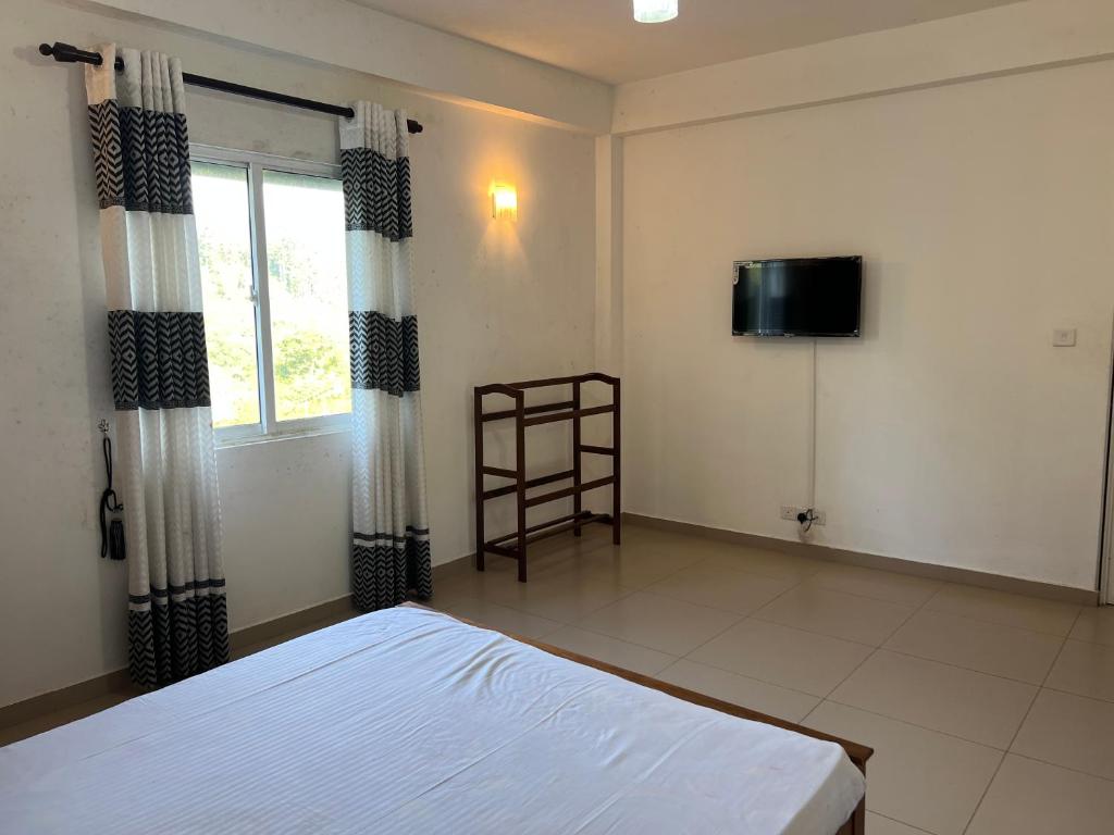 Crimple cottage في نوارا إليا: غرفة نوم مع سرير وتلفزيون بشاشة مسطحة