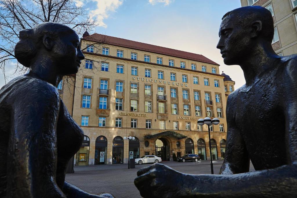 Une statue de deux femmes devant un bâtiment dans l'établissement Steigenberger Icon Grandhotel Handelshof Leipzig, à Leipzig