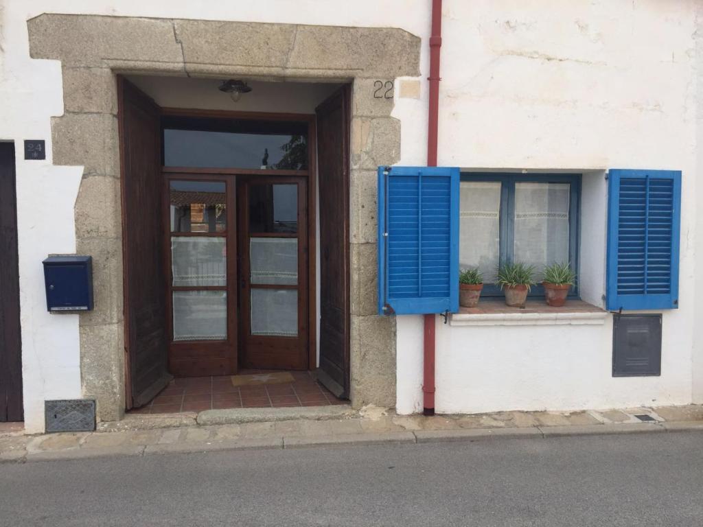 una puerta y una ventana con persianas azules en un edificio en El Terral en Sant Vicenç de Montalt