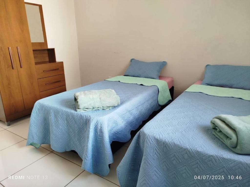a bedroom with two beds with blue sheets and a mirror at Unidade 2 in Bauru