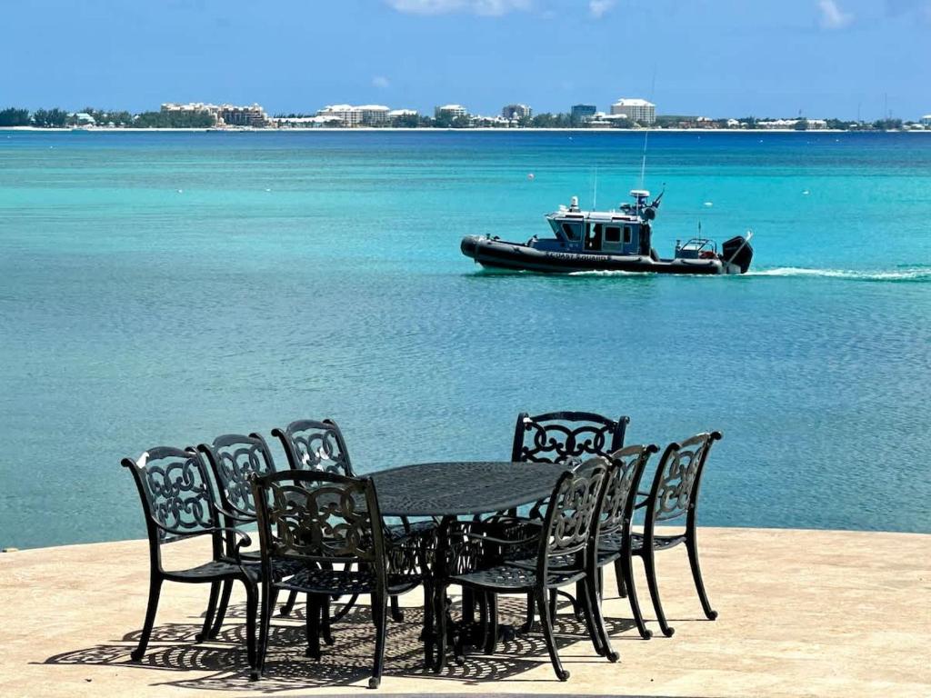 a table and chairs with a boat in the water at Seven Mile View Condo #3B in West Bay