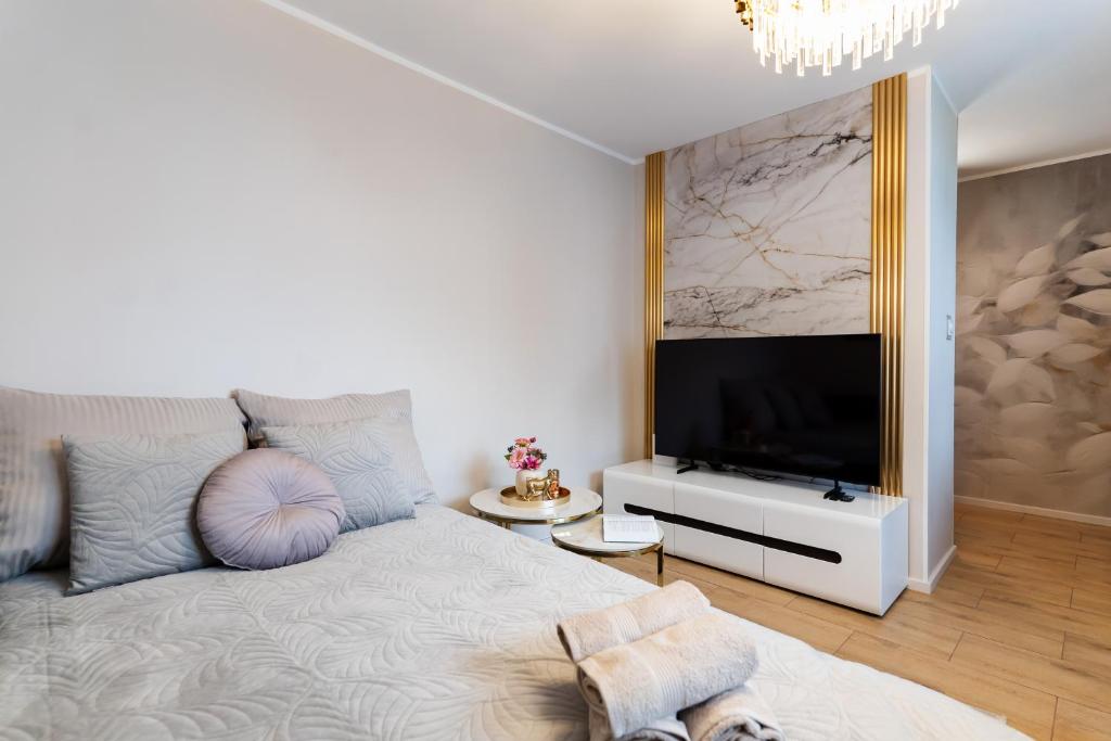 a bedroom with a large bed and a television at Apartament Alchemia Gór in Złoty Stok