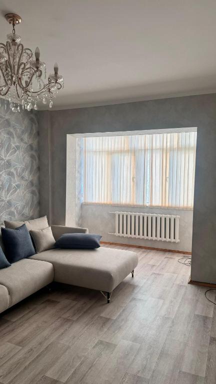 a living room with a couch and a window at Flat with 3 rooms near parks in Bishkek