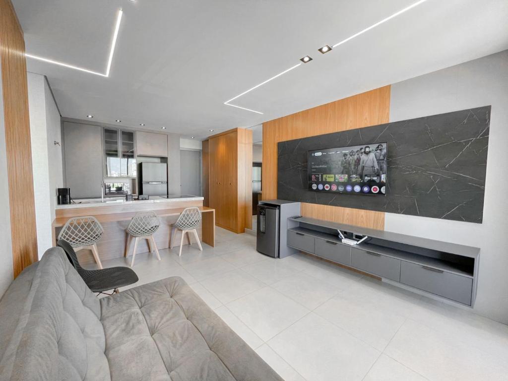 a living room with a couch and a flat screen tv at Flat Espaçoso com Uma Bela Vista e 2 Quartos in Campo Grande