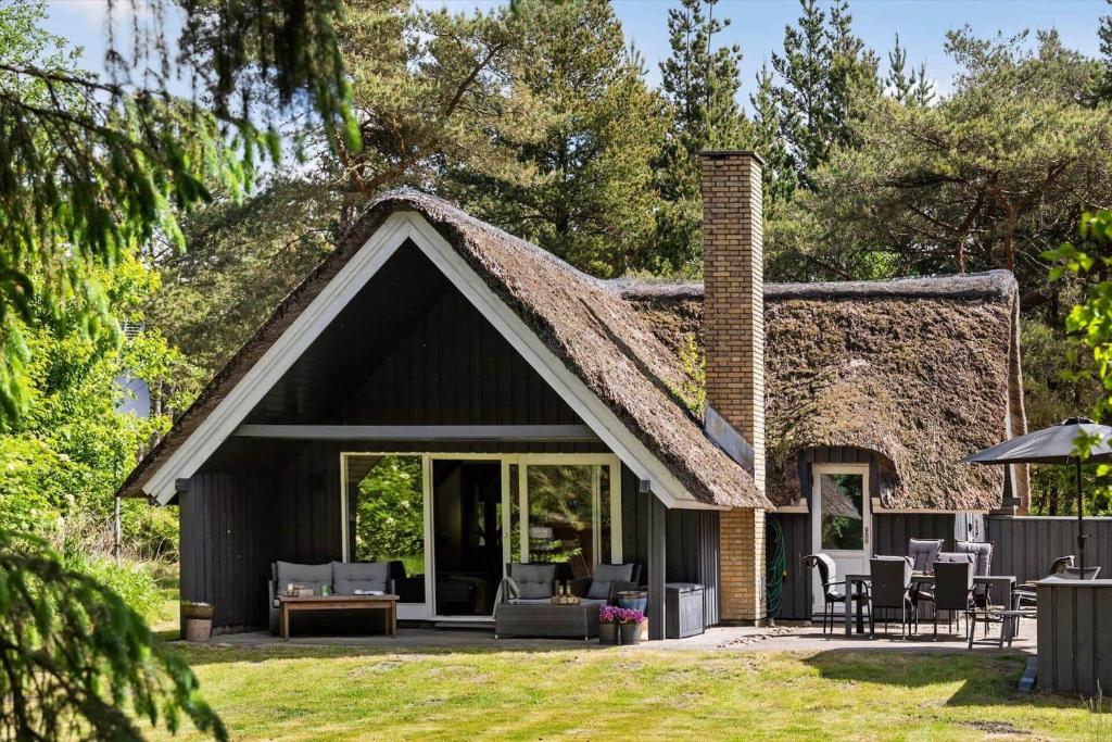 a house with a thatched roof with a patio at 0337-Romo-Kliren-1 in Høm