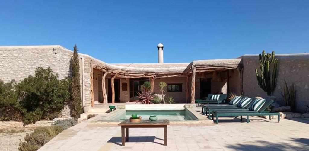 a patio with two green benches and a pool at Dar Tikida - Luxury Beach Villa - 8 people in Sidi Kaouki