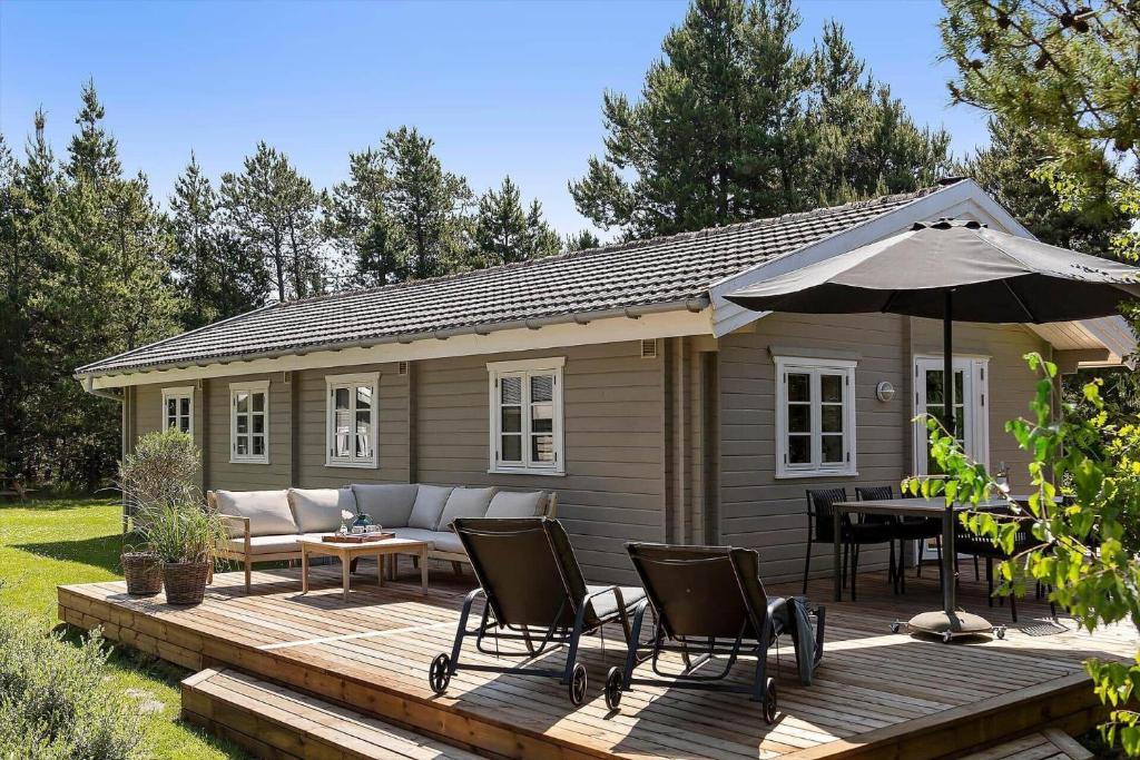 a house with a deck with chairs and an umbrella at 0311-Romo-Strandskaden-10 in Høm