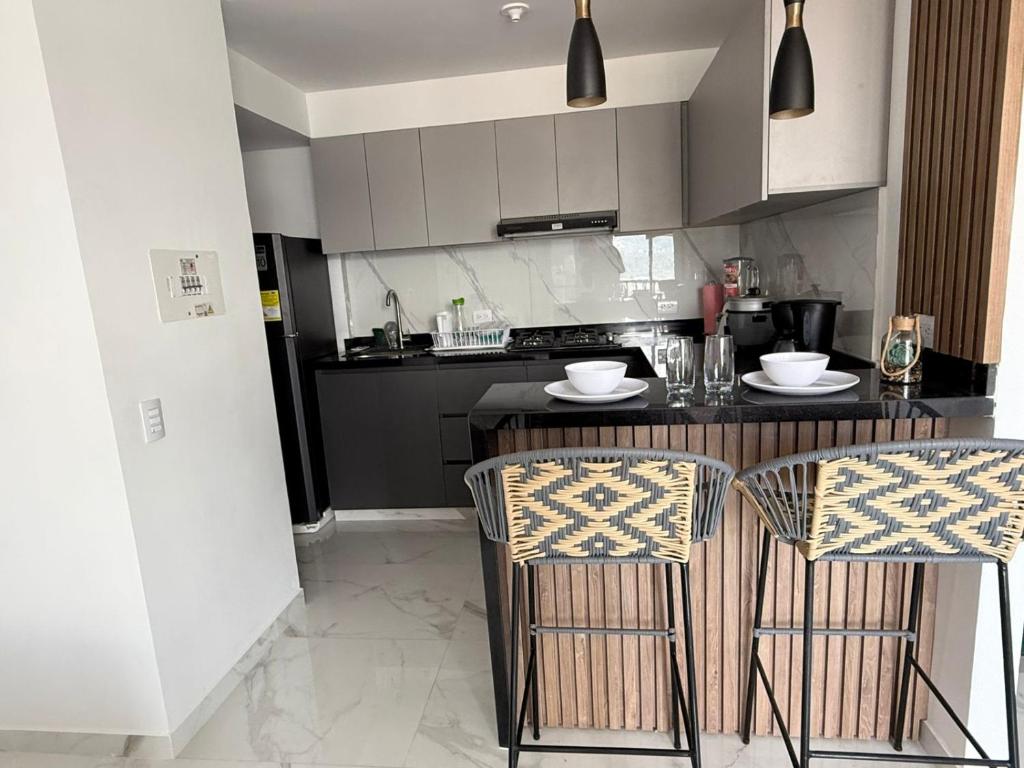 a kitchen with a counter and two bar chairs at apartamento amoblado en la foscal in Floridablanca
