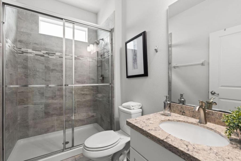 une salle de bain avec une douche, des toilettes et un lavabo dans l'établissement Ultimate 8br Family Getaway, à Kissimmee