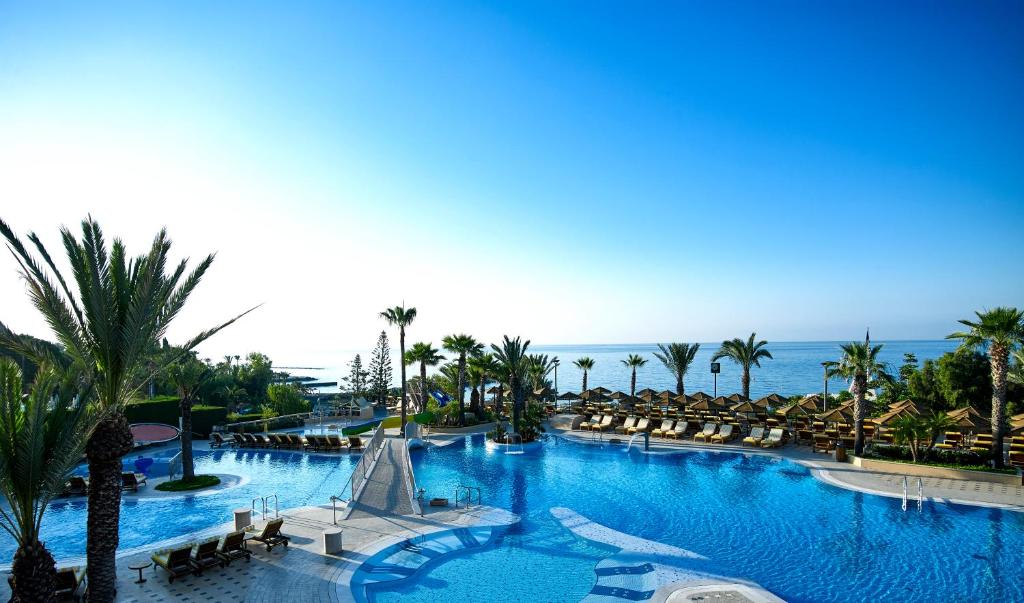 een groot zwembad met palmbomen en de oceaan bij Four Seasons Hotel in Limassol