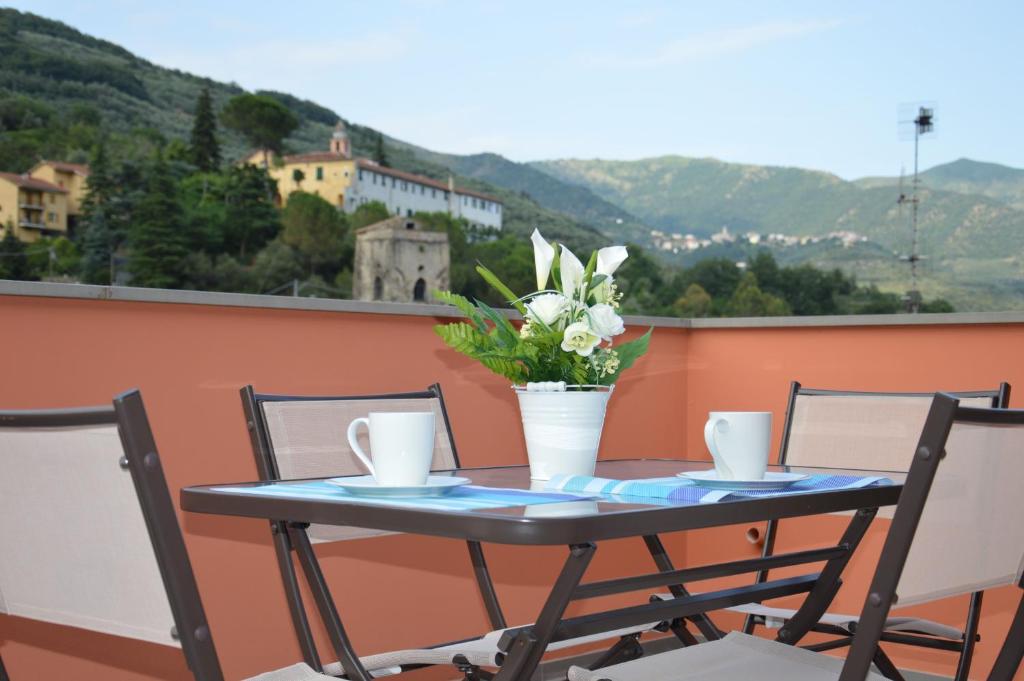 a table with chairs and a vase of flowers on a balcony at Il Cuore del Borgo - Holiday Home in Borgomaro