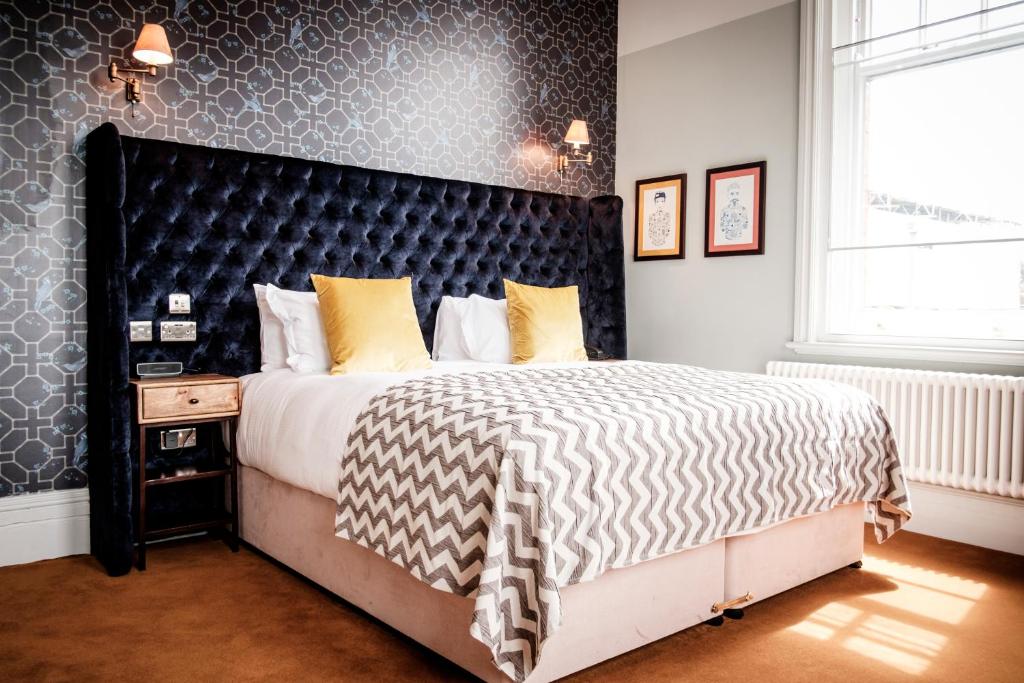 a bedroom with a large bed with a black headboard at The Queen's Head in Kingston upon Thames