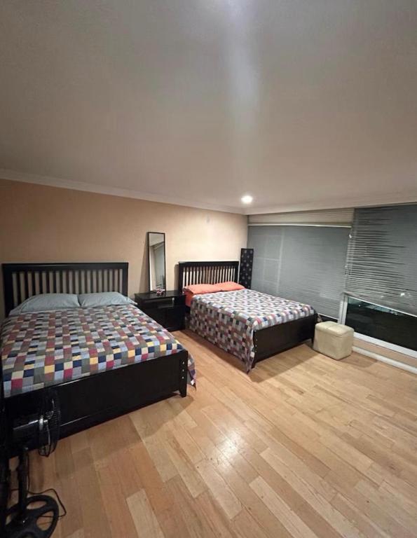 Zwei Betten in einem großen Zimmer mit Holzboden in der Unterkunft Los Colibries in Mexiko-Stadt