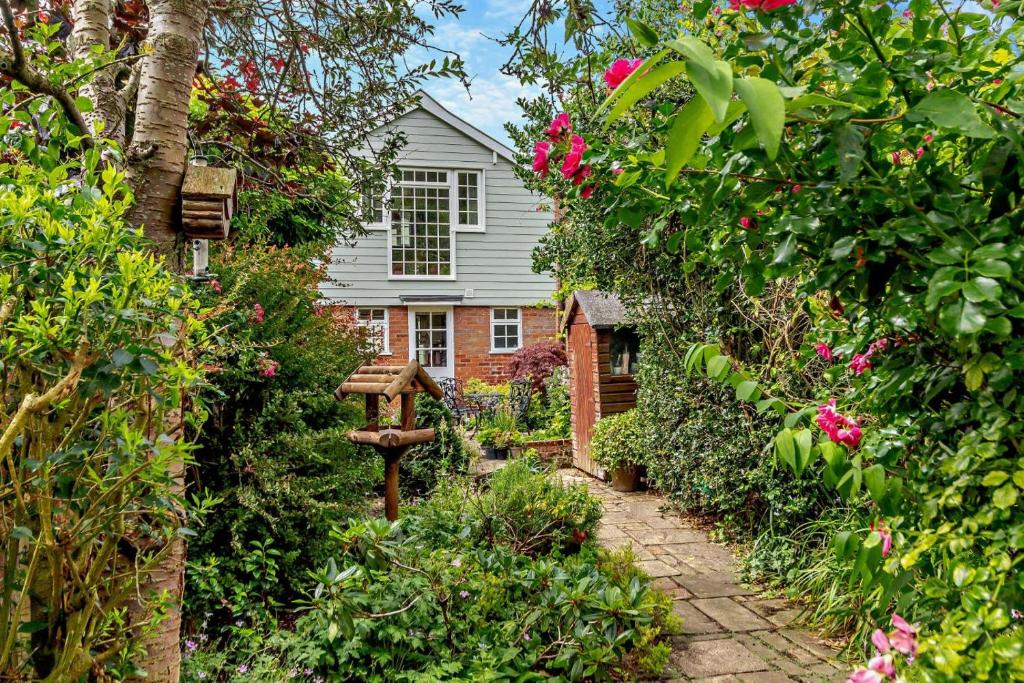 un jardin fleuri et une maison en arrière-plan dans l'établissement Coach House Cottage Annexe, à Wickham Market