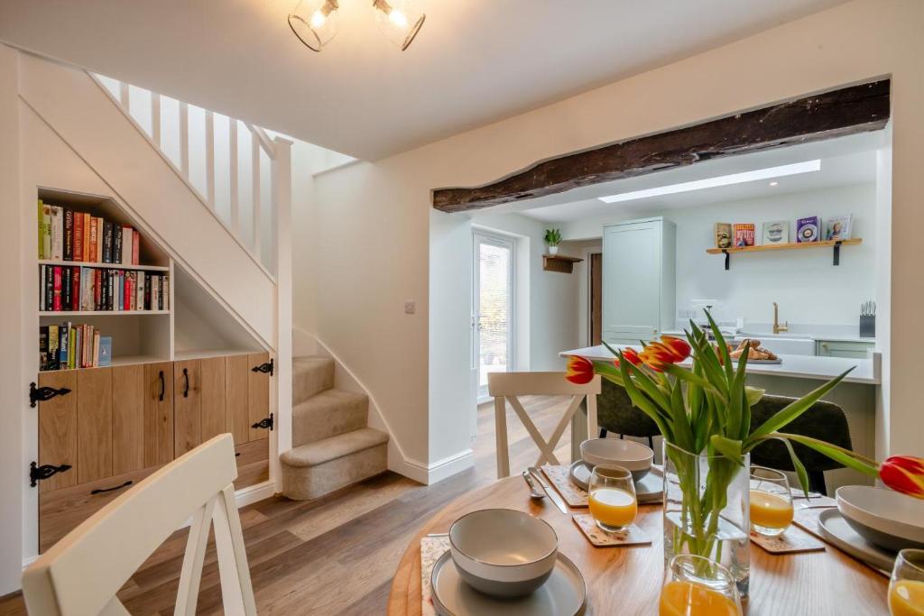 - une cuisine et une salle à manger avec une table fleurie dans l'établissement Stone Cottage, à Aylsham