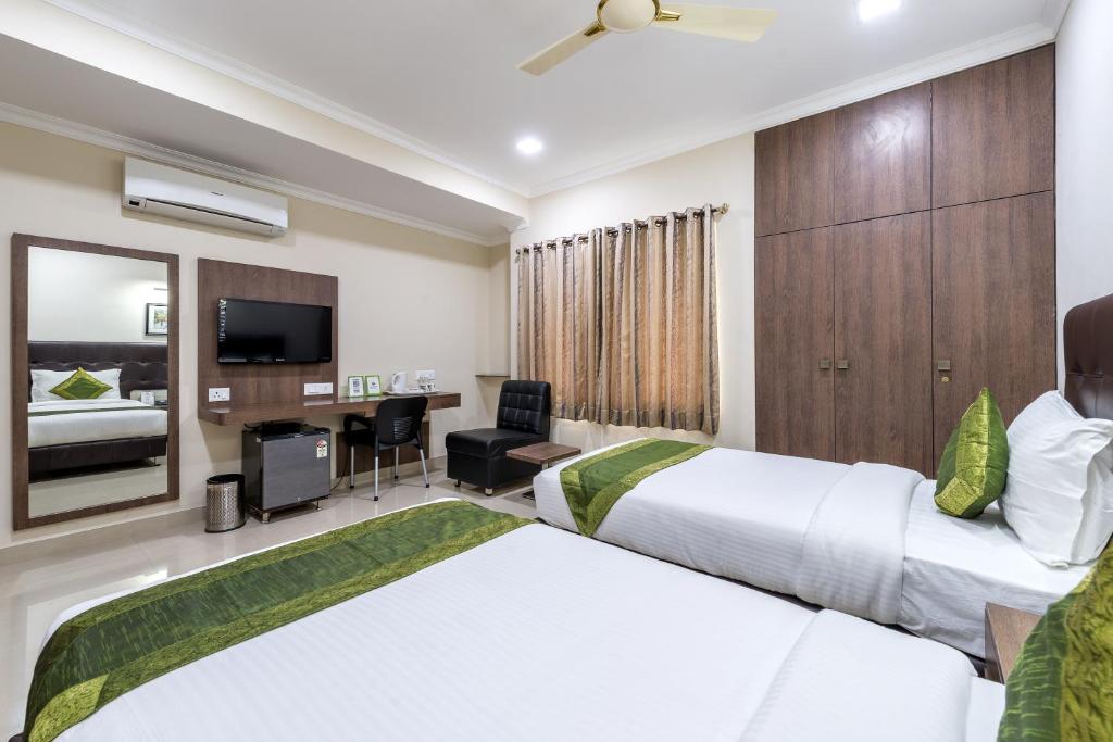 a hotel room with two beds and a desk at Hotel Mount Kailash Suites in Chennai