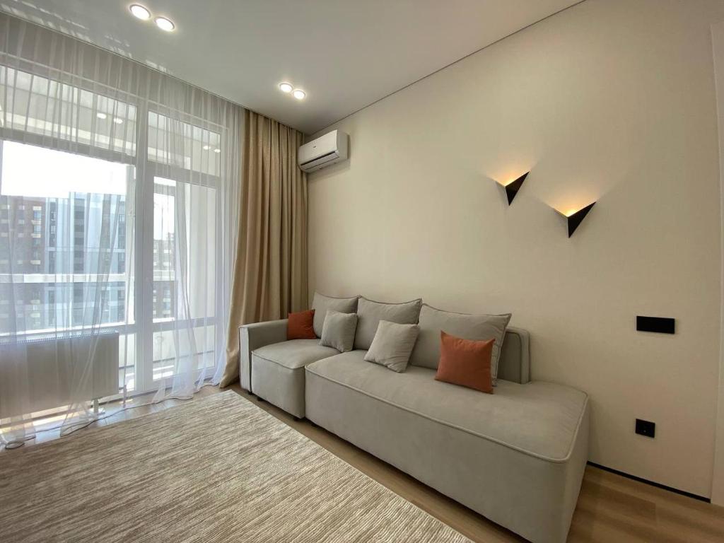 Una sala de estar con un sofá y una ventana grande. en Luxury Apartament, en Astana