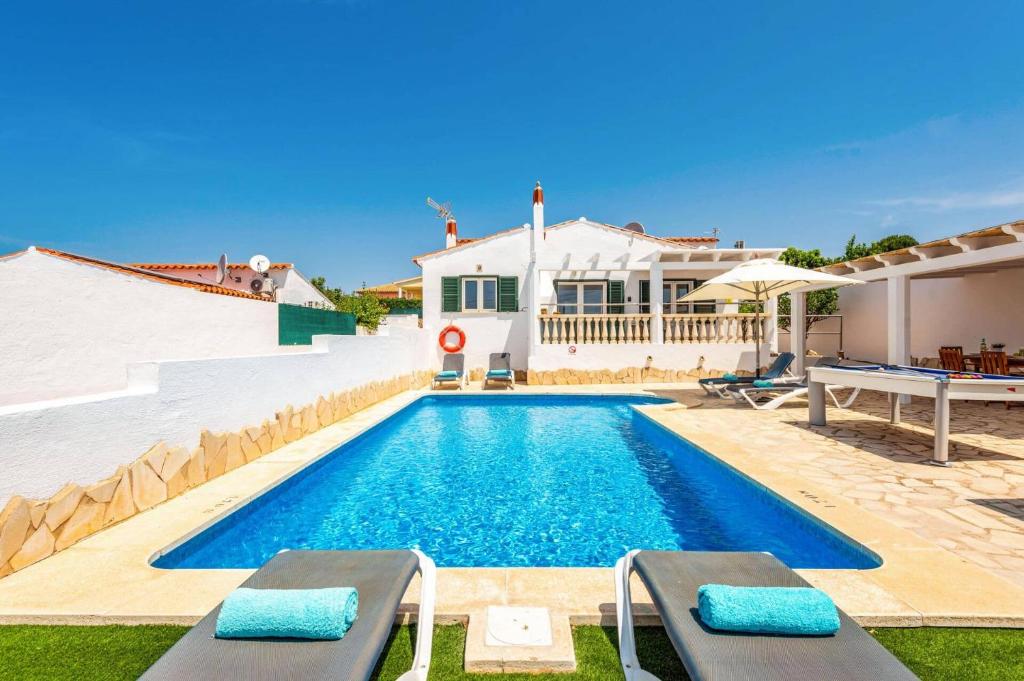 a swimming pool with two chairs and a house at Villa Airosa by Villa Plus in Cala'n Porter