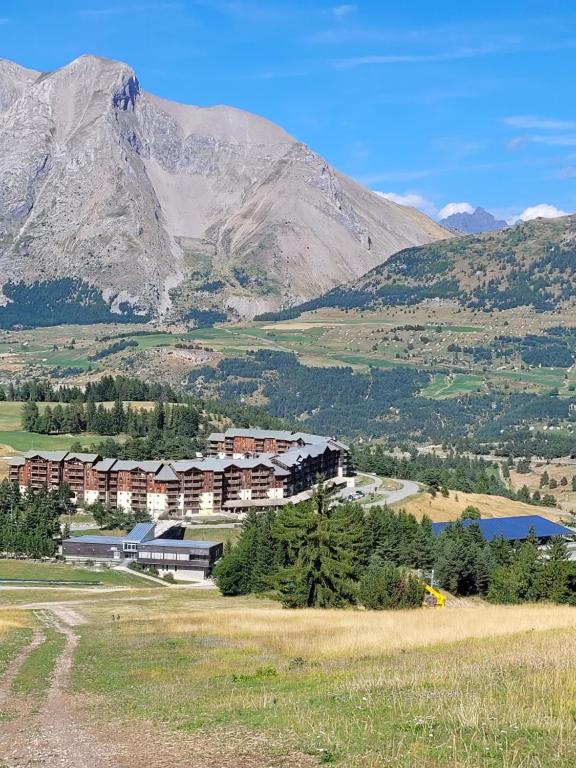 un bâtiment dans un champ avec des montagnes en arrière-plan dans l'établissement Appart vue montagne Le Devoluy, à Saint-Étienne-en-Dévoluy