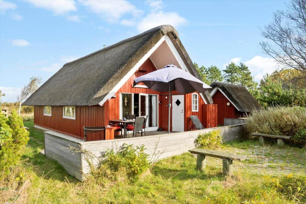 a red house with a thatched roof with an umbrella at 0009-Romo-Thadesvej-37 in Høm