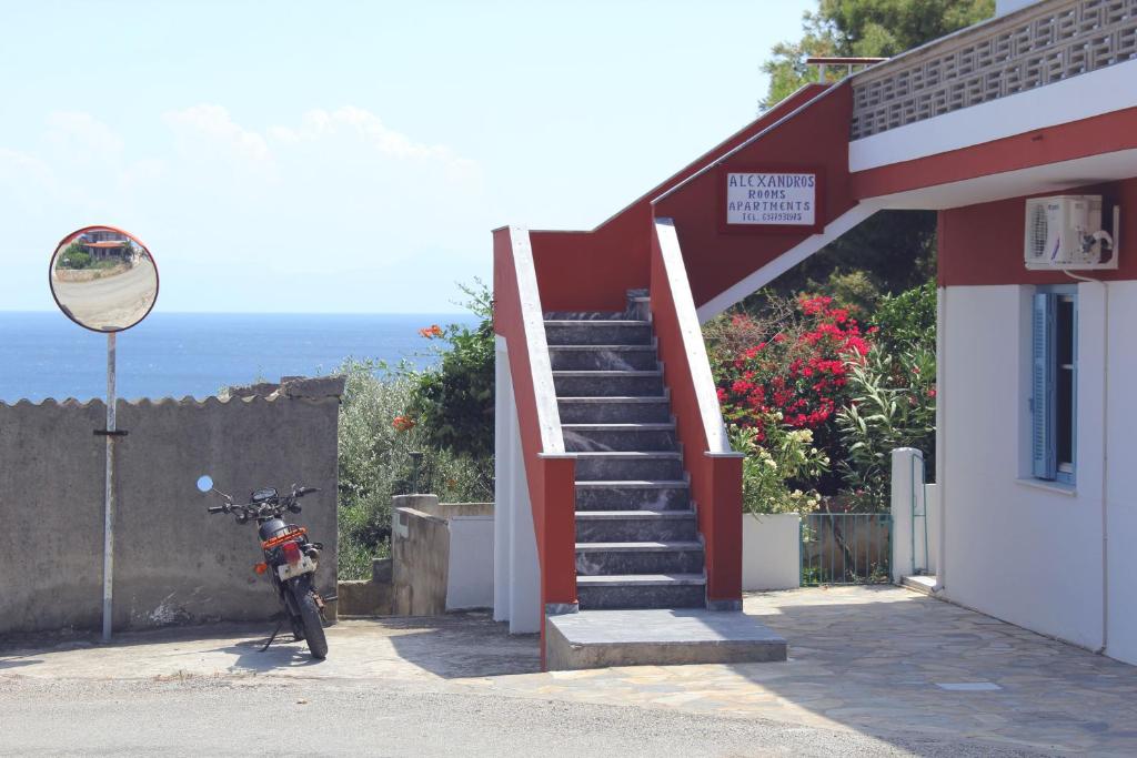 a motorcycle parked next to a building with a staircase at Αlexandros apartment in Votsi