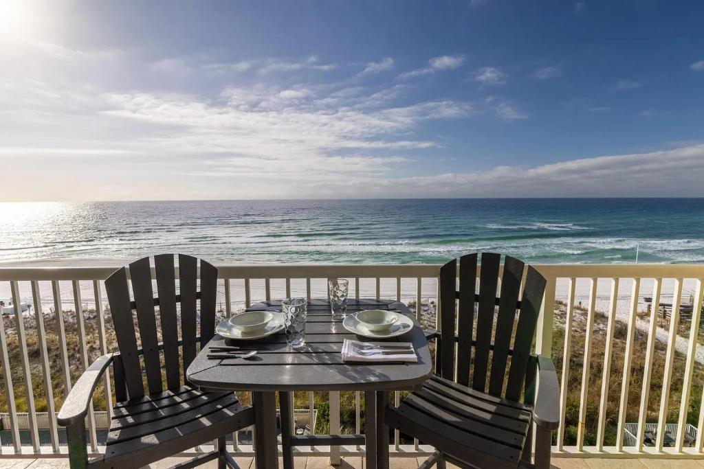 a table and chairs on a balcony with the ocean at Waters Edge 606 - Oceanfront - Free Beach Service - Breathtaking Views in Fort Walton Beach