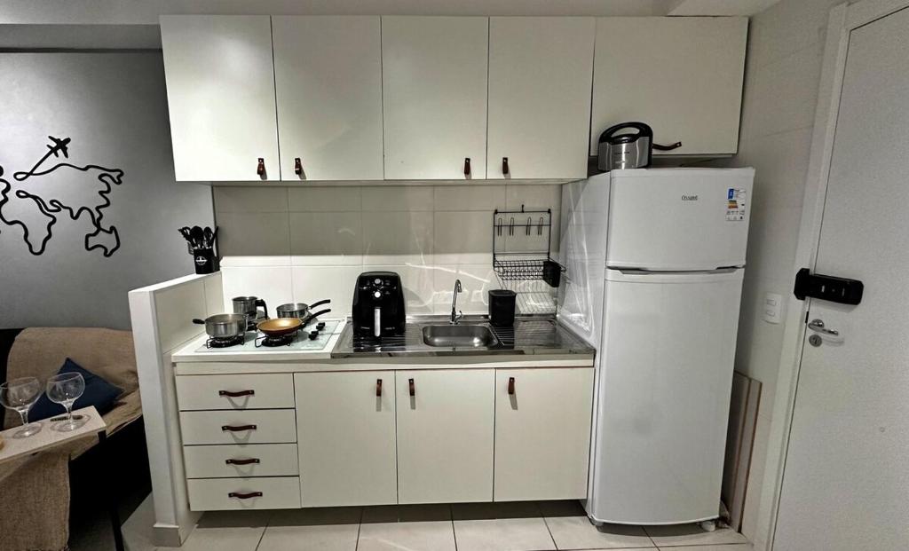 a kitchen with white cabinets and a white refrigerator at Ao Lado de Empresas e Eventos SP in Sao Paulo