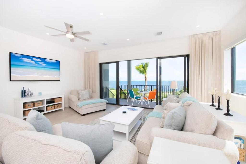 a living room with white furniture and large windows at Cassava Pointe 4D at Sea Haven in Omega Gardens