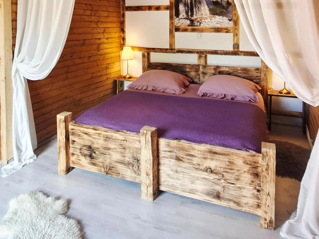a bedroom with a wooden bed with purple sheets at Etno wooden room in Rakovica