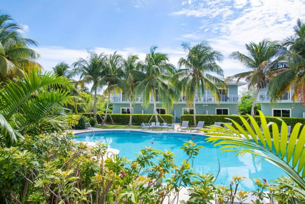 a swimming pool in front of a resort with palm trees at Summertime Suites #50 in West Bay