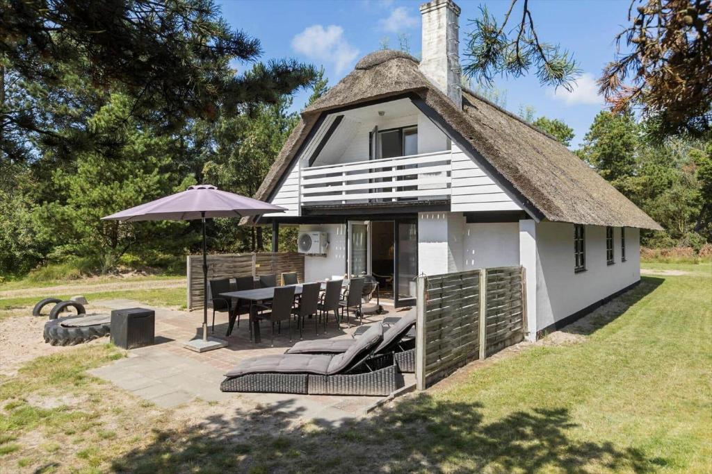 a white house with a table and chairs and an umbrella at 0339-Romo-A-Hveyselsvej-32 in Rømø Kirkeby