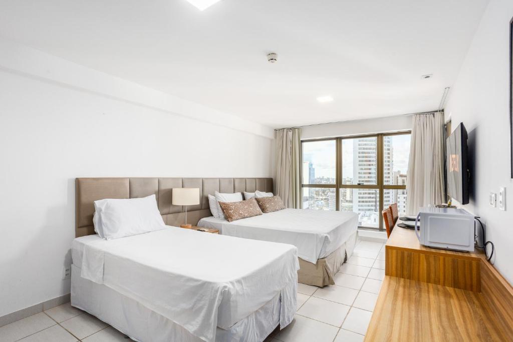 Una habitación de hotel con dos camas y un televisor. en BEIRA MAR- FLAT EXECUTIVE, en Recife