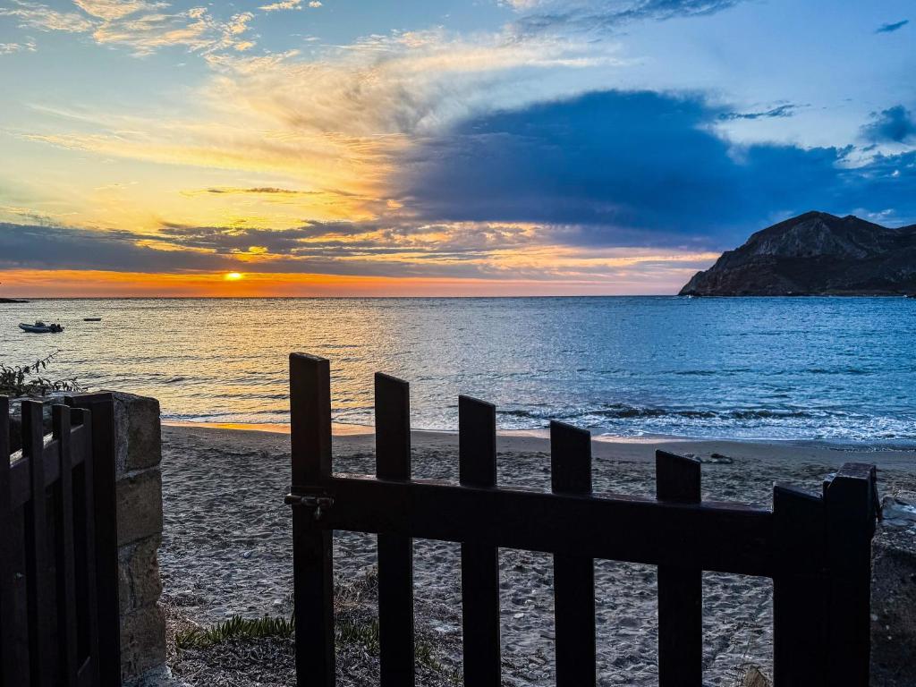a sunset over the ocean with a fence on the beach at Mealos Apartments in Skiros