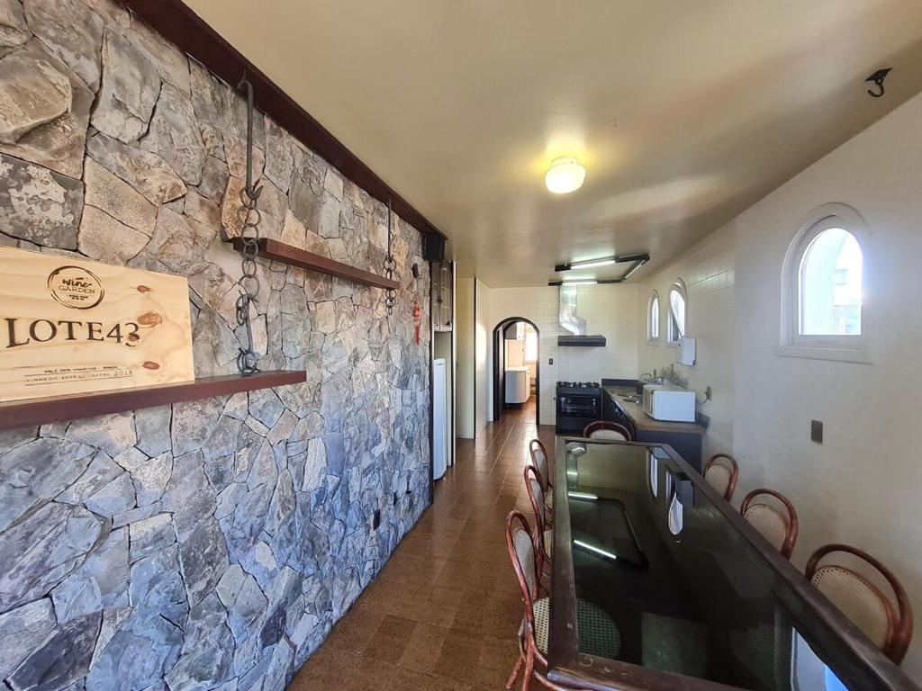 a dining room with a stone wall and chairs at Apartamento ao lado do Shopping Lamérica in Bento Gonçalves