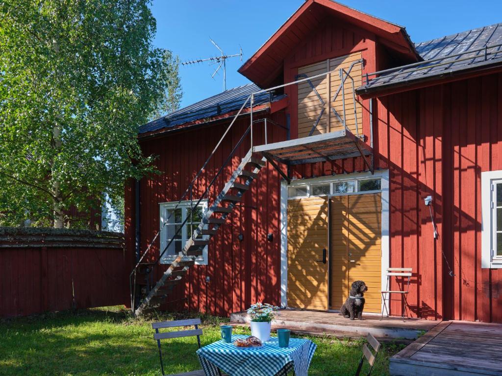 un perro sentado en el porche de una casa roja en Jädraås sjösida, en Jädraås